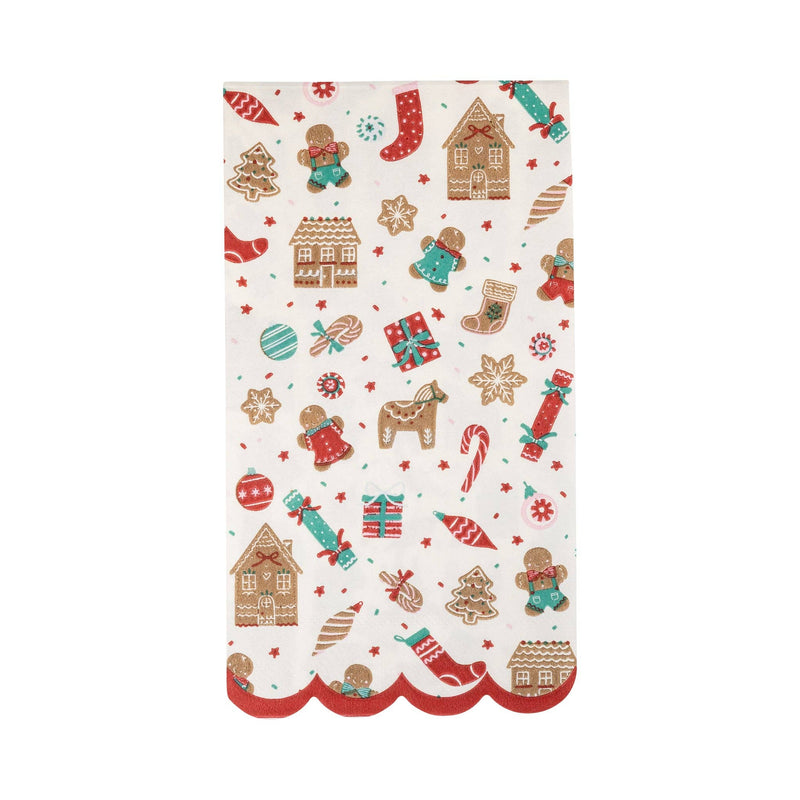 Flat lay of an unfolded Gingerbread Pattern Dinner Napkin featuring gingerbread houses, cookies, and candy canes with a red scalloped edge.
