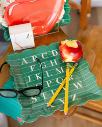 Close-up of back to school breakfast table featuring green alphabet plate with apple and pencils