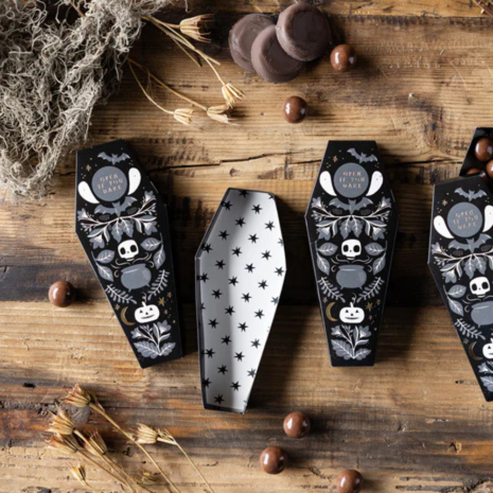 Open Coffin Treat Box with star-patterned interior filled with candy on a rustic table.
