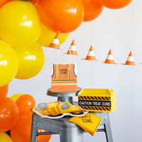 Table setup with construction-themed party items, including vest treat bag labeled "Work Zone"