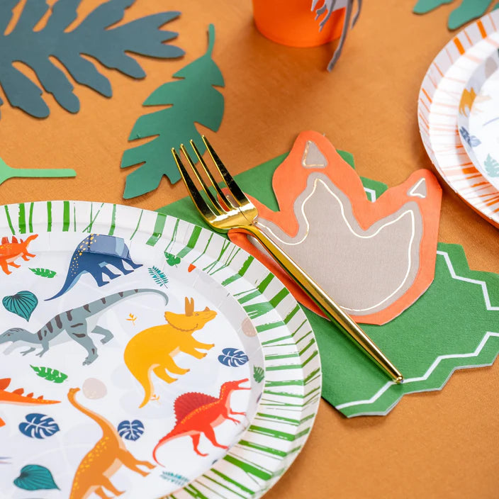 Gold fork resting on dinosaur footprint napkin next to leaf decor.