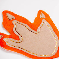 Closeup of gold foil dinosaur footprint napkin edge on orange border.