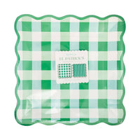 Gingham and stripe green paper plates stacked with scalloped edges in packaging