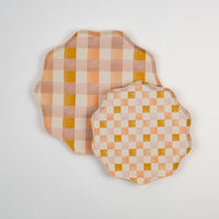 Set of coordinating pastel checkered and plaid paper plates in peach, blush, and mustard hues with scalloped edges. Ideal for layered table settings at boho, garden, or bridal showers.