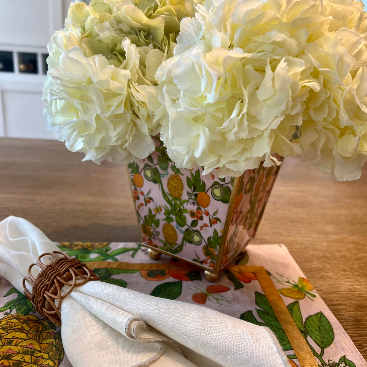 Make a statement with our Enameled Square Cachepot Planter, a playful yet practical table centerpiece. Decked out in a vibrant palette and a fruity motif of pineapples, limes, and oranges, this cachepot is trimmed in gold for that extra sparkle. Whether you're looking to brighten up your office desk, kitchen counter, or dining table, it offers a splash of spring and summer all year round. Versatile and visually stunning, it’s the centerpiece that brings your tablescape ideas to life.