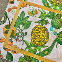 Transform your table setting with our Pineapple Garden Enameled Rectangle Placemats. This set of four summer placemats, crafted from textured 100% cotton, features a delightful design of pineapples, limes, and oranges, accented with an orange ribbon trim. They're not just placemats—they're a statement piece and an excellent choice for a hostess gift or personal treat.
