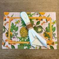 Transform your table setting with our Pineapple Garden Enameled Rectangle Placemats. This set of four summer placemats, crafted from textured 100% cotton, features a delightful design of pineapples, limes, and oranges, accented with an orange ribbon trim. They're not just placemats—they're a statement piece and an excellent choice for a hostess gift or personal treat.