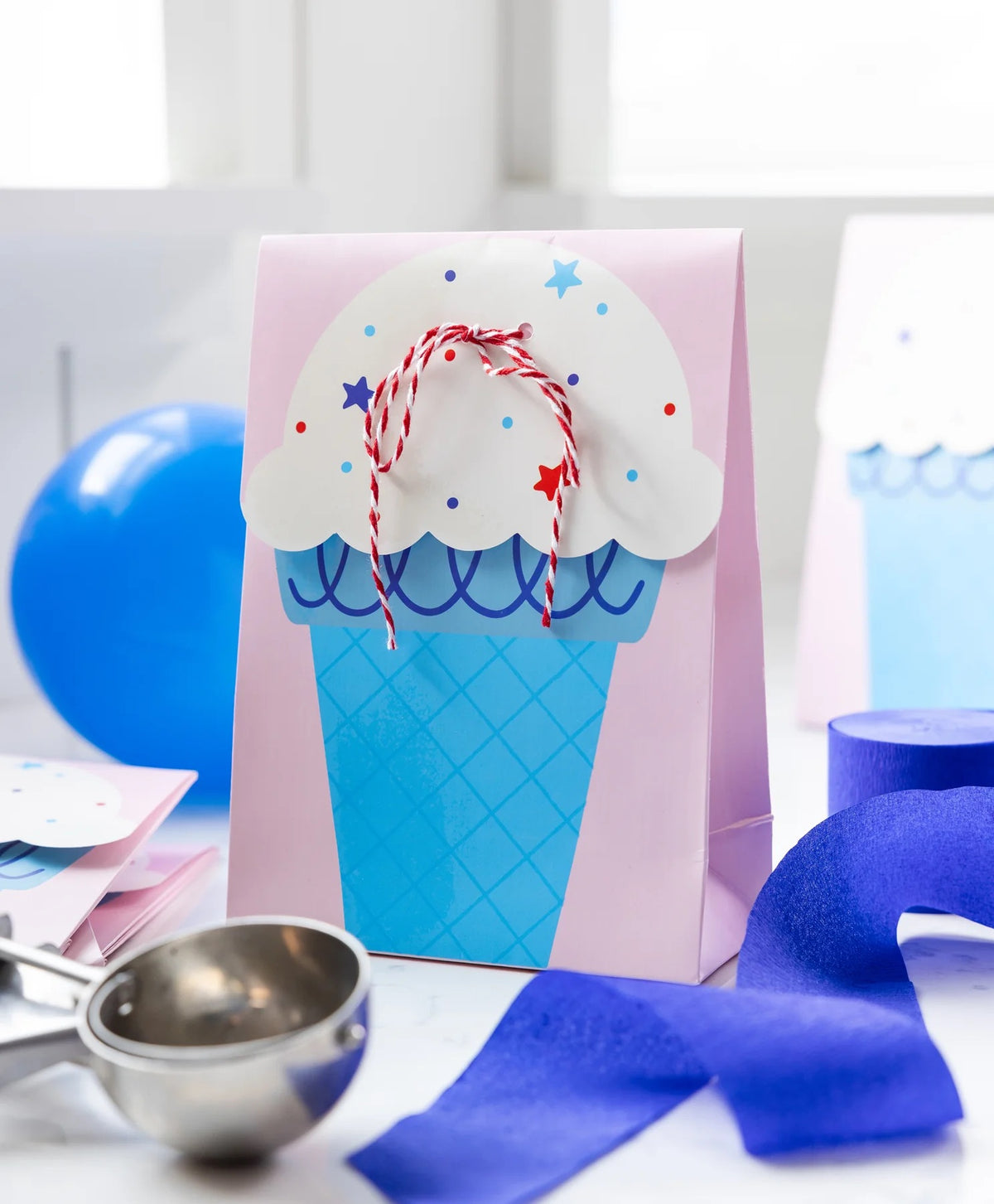 Pastel pink treat bags with ice cream designs, tied neatly with striped twine for kids' birthday parties.