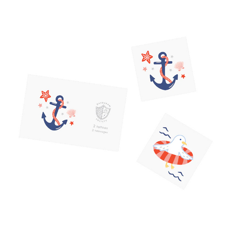 Image shows two seaside-themed temporary tattoos—one with an anchor wrapped in red rope and surrounded by shells and stars, and one with a seagull floating in a red-striped pool ring.