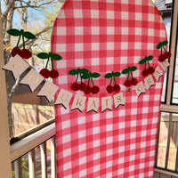 Shirley She Didn't Graduate party setup with cherry banner and red gingham backdrop