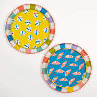A stylish arrangement of summer-themed plates layered on striped charger plates, showcasing their fun poolside vibe with bold, retro colors.