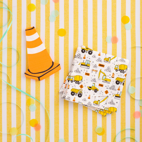 Flat lay of orange and white traffic cone-shaped napkin next to striped paper napkin on a yellow background.