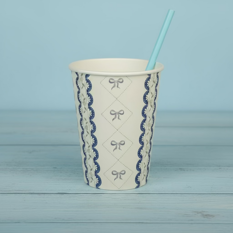 Blue coquette cup with a blue paper straw on a light wood background