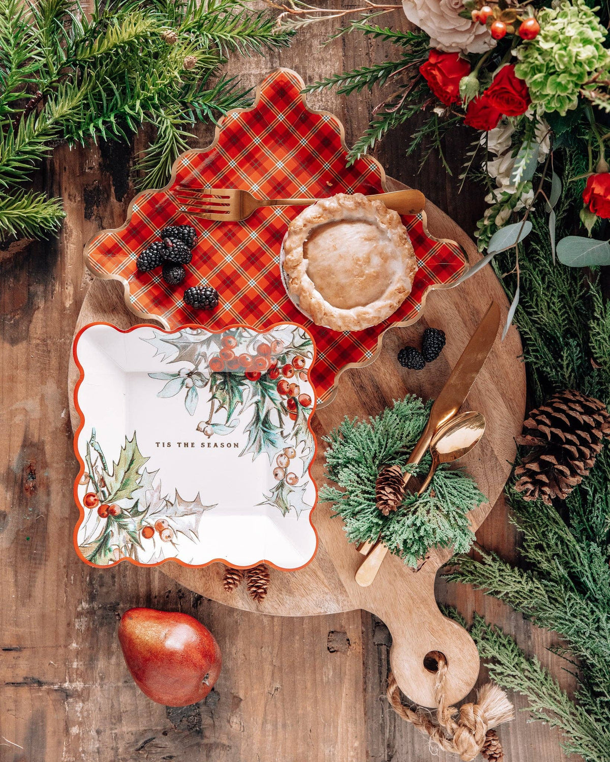 Red plaid plate styled for holiday dessert with berries and greenery