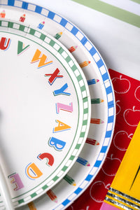 Close-up of alphabet paper plate and pencil-rim paper plate edges on a red apple-print paper runner