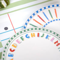 Close-up of alphabet paper plate and pencil-rim paper plate showing the green checkered border, multi-color alphabet letters, and colored pencil illustrations