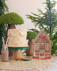 Table scene with a frosted cake, milk bottle, and Ginger House Plate in a festive holiday setup.