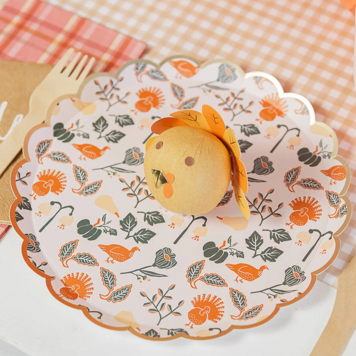 Close view of scalloped dessert plate with gold rim and turkey-and-gourd pattern.