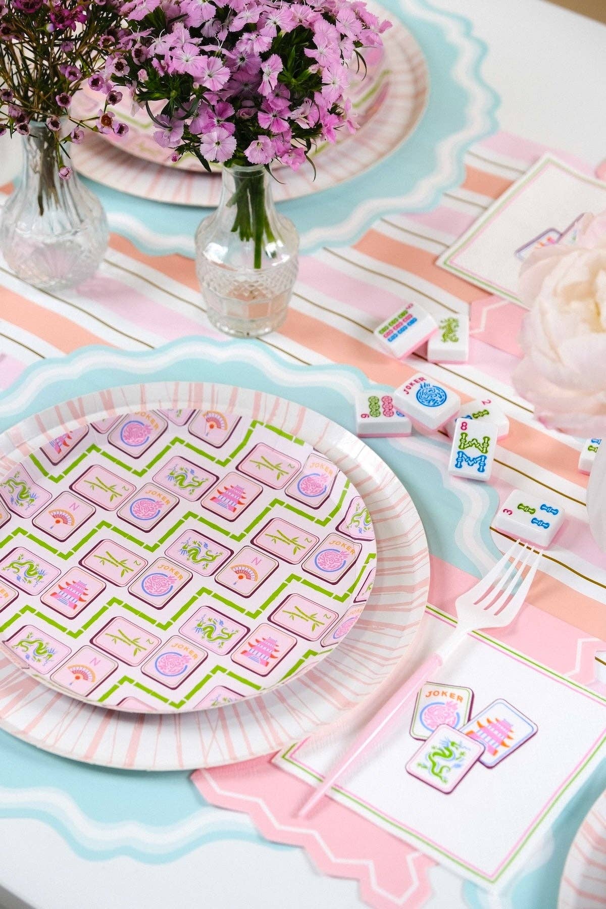 Pastel-colored table setting with paper plates, napkins, and flowers.