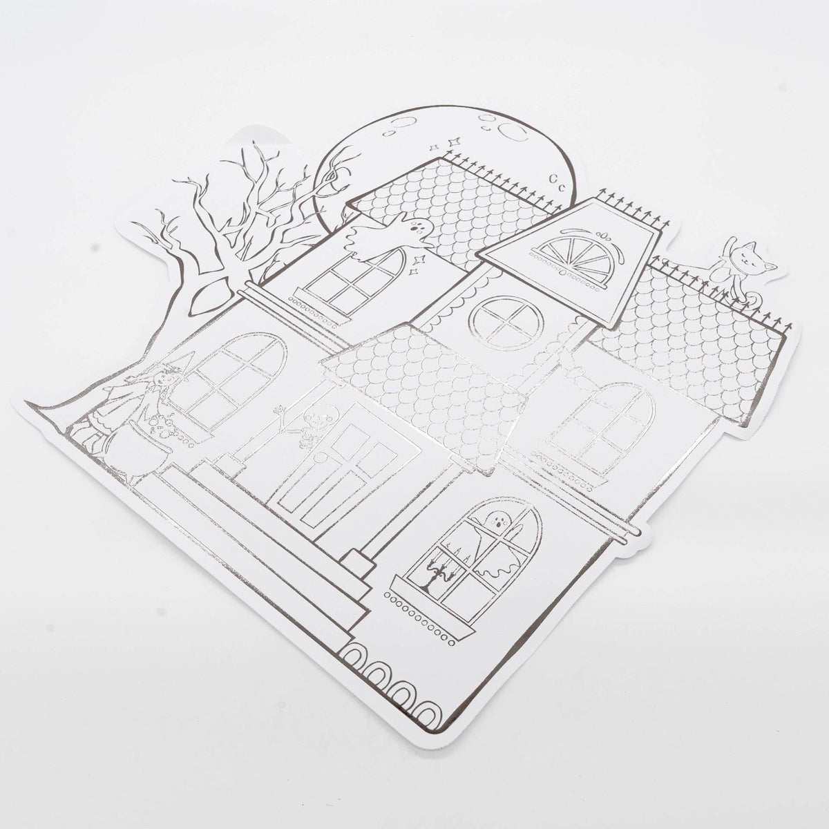 Angled studio shot of the die-cut haunted house placemat highlighting the metallic gunmetal foil shine reflecting light.