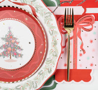 Close-up angled view of a vintage Christmas tree holiday plate on a red scalloped charger next to the pink present napkin.