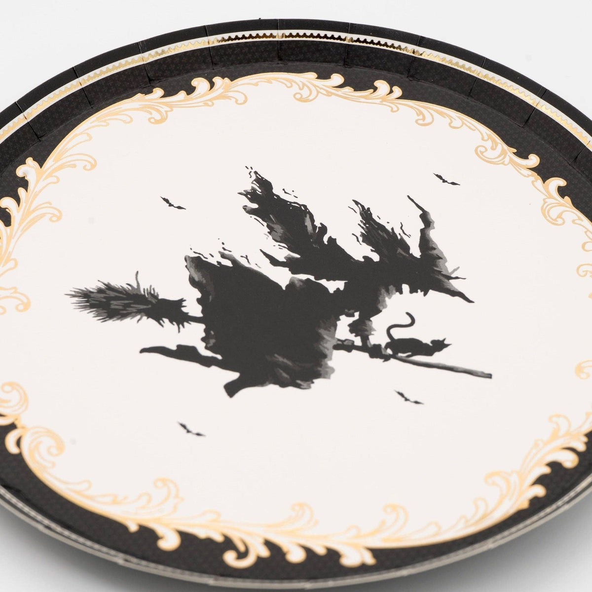 Angled studio shot of the round vintage witch silhouette paper dessert plate showcasing its glossy finish and gold accents.