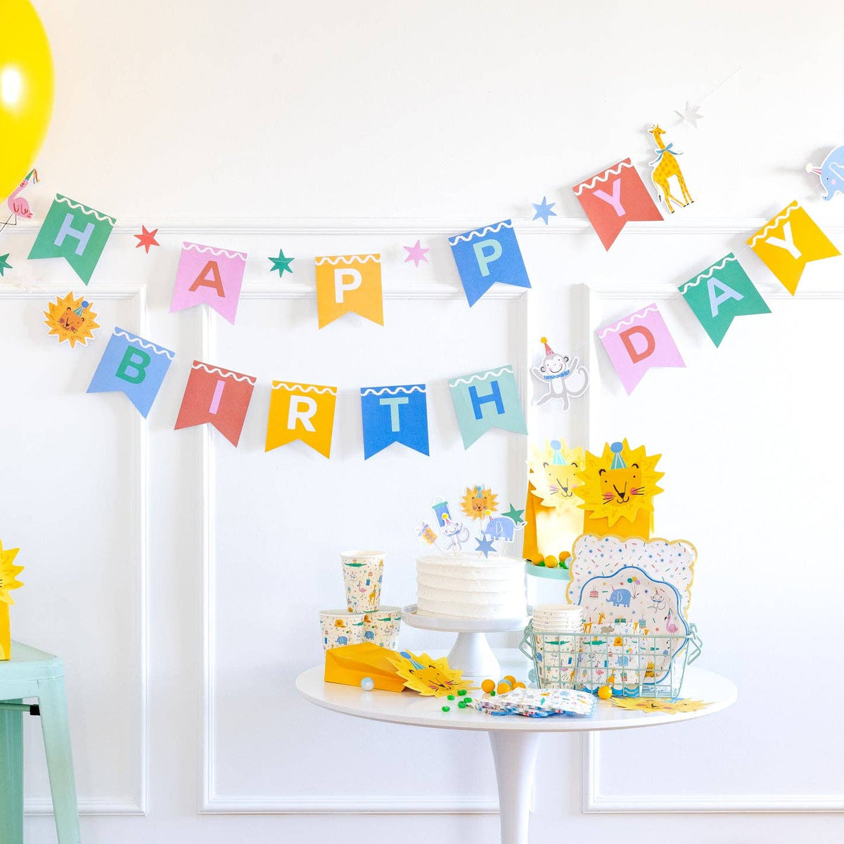 Animal party birthday setup featuring banner, plates, cups, and decorations.