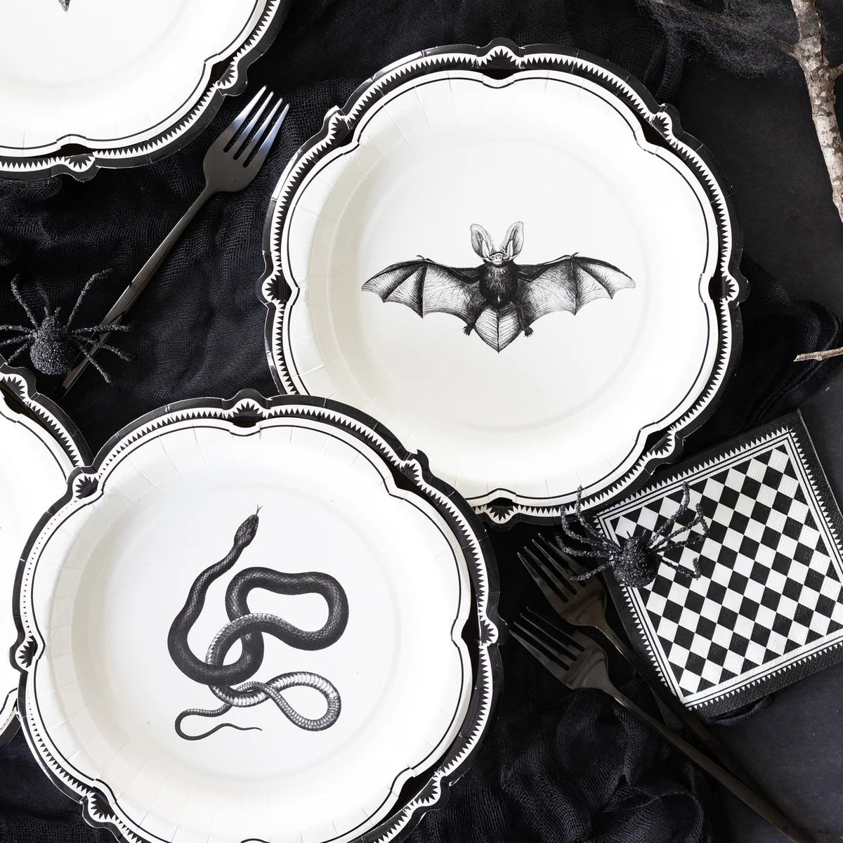 Halloween-themed plates with black animal illustrations on a dark surface.