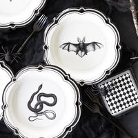 Halloween-themed plates with black animal illustrations on a dark surface.