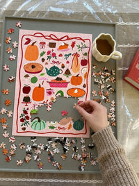 Autumn harvest 500 piece puzzle with pumpkins, pies, and apples being put together on a tray with a cup of coffee