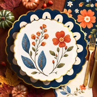 Close-up of a wildflower plate on a navy scalloped plate beside gold flatware and navy floral napkins