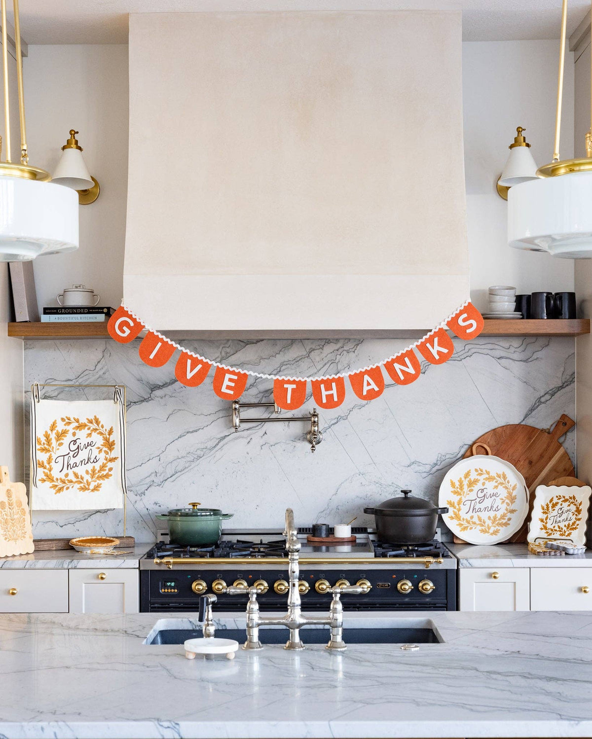 Rustic Give Thanks felt garland hanging beautifully above a modern white kitchen stove hood for cozy fall interior styling.