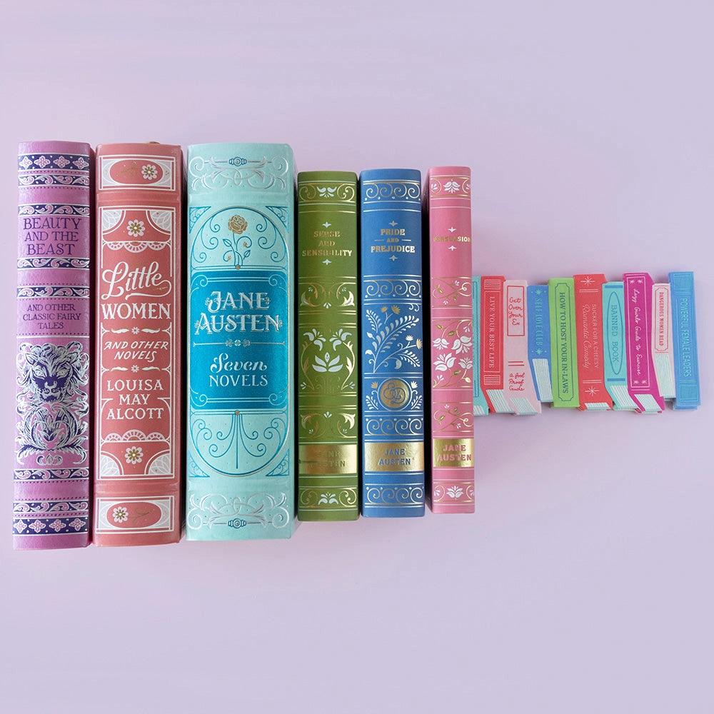 Row of pastel hardcover novels with matching die-cut book stack paper napkins on lavender background.