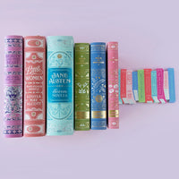 Row of pastel hardcover novels with matching die-cut book stack paper napkins on lavender background.