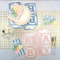 Tablescape with blue and pink Baby Blocks paper placemats, coordinating plates and napkins—styled baby shower table decorations.