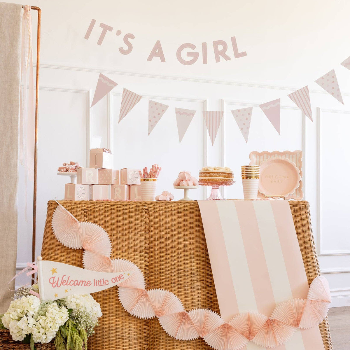 Baby pink banner set with It’s a Girl letters and pink pennants used as baby girl party decorations for a baby shower.