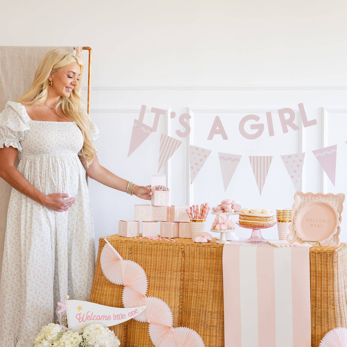 Baby pink banner with “It’s a Girl” lettering styled above a dessert table for a baby shower, featuring soft pink pennants and coordinated party decor.