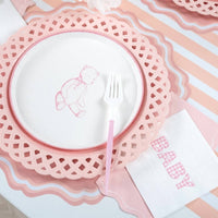 Styled baby shower place setting showing the pink napkin with a bunny plate on a pink scalloped charger and pink-striped runner.