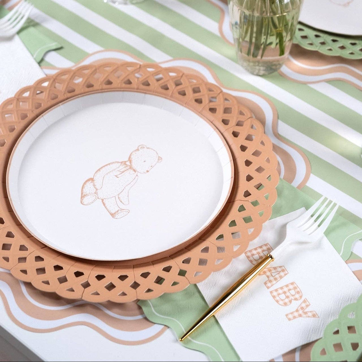 Styled baby shower place setting showing the sage napkin with a bunny plate on a tan scalloped charger and green-striped runner.