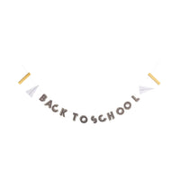 Back to School banner garland strung between paper airplanes and gold rulers, shown hanging on a white background.