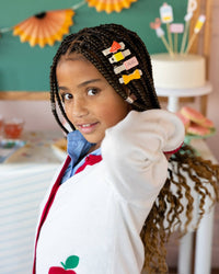 Close-up of young girl with braids wearing four back to school hair clips including YAY megaphone, pencil, pink eraser, and ruler bow