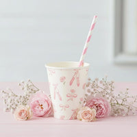 Ballerina cup on a pink table with a striped straw and fresh roses