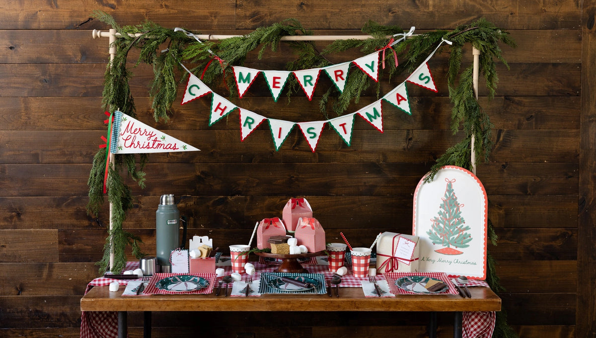 Rustic table with the bamboo tray, a Merry Christmas pennant banner, and a dessert spread.