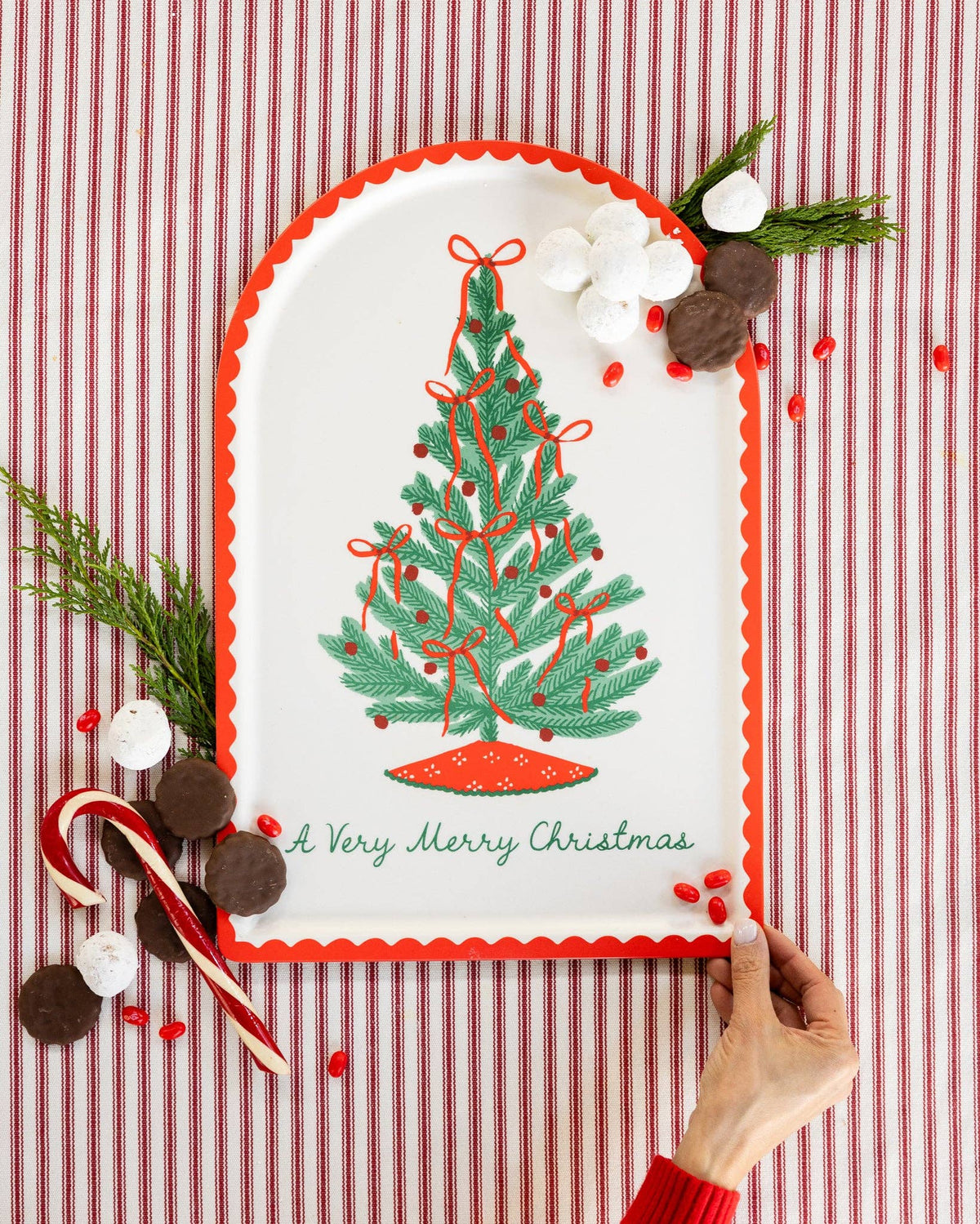 The Christmas tree bamboo tray styled against a red-striped backdrop with a candy cane and greenery.