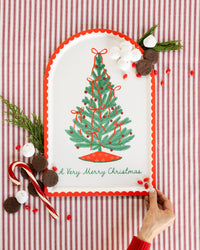 The Christmas tree bamboo tray styled against a red-striped backdrop with a candy cane and greenery.