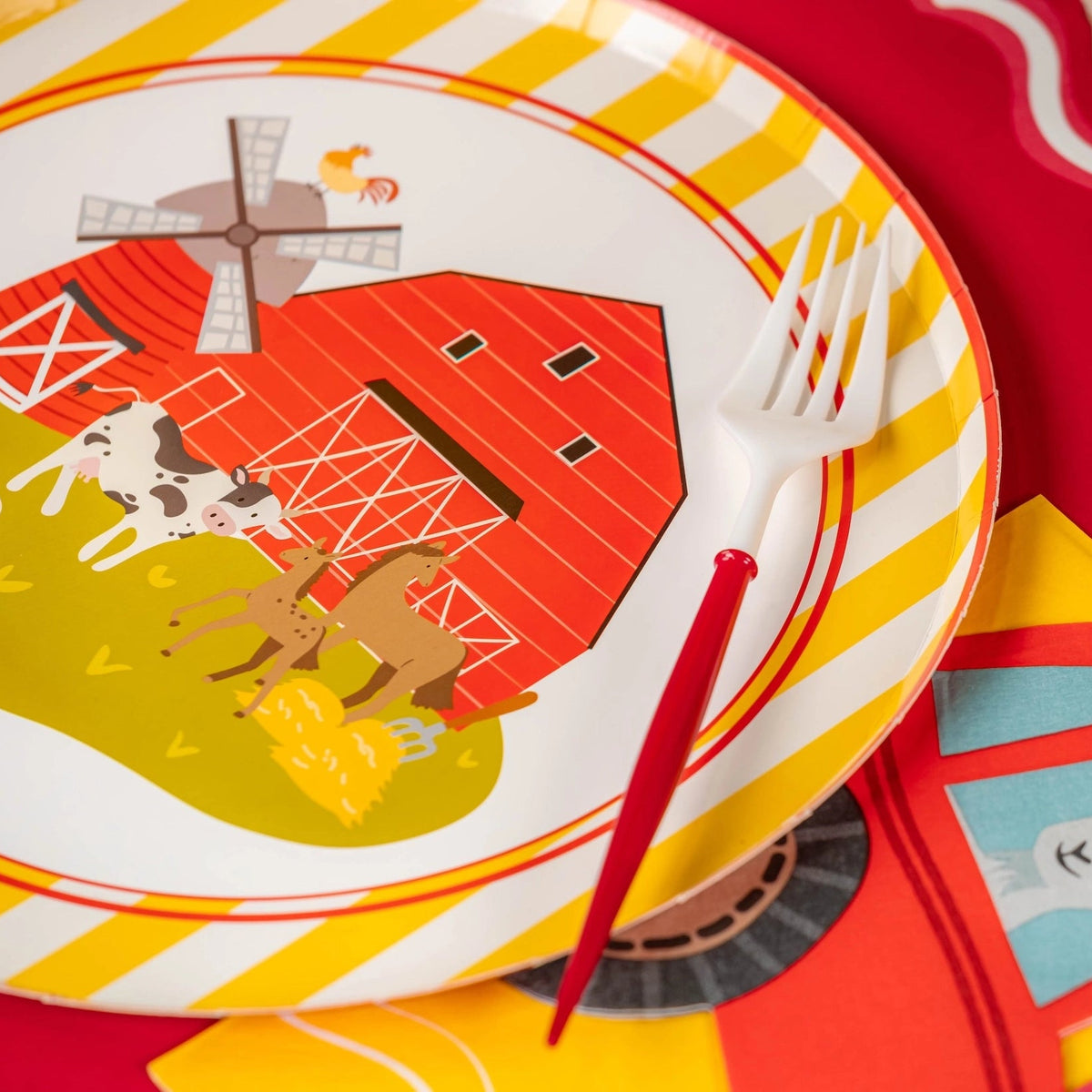 Angle shot of plate showing cow, horse, pig near red barn.
