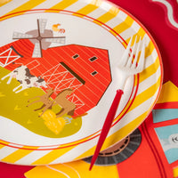Angle shot of plate showing cow, horse, pig near red barn.