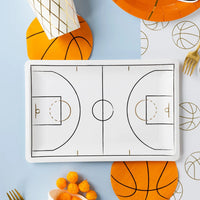 Overhead party scene with court plate, snacks, and gold flatware.