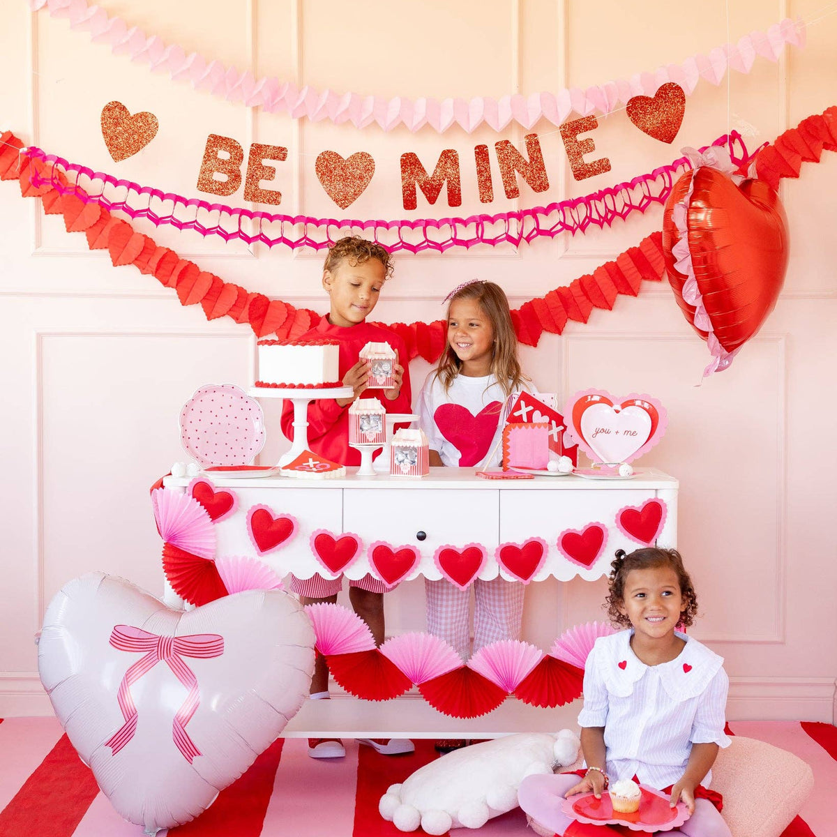 Children celebrating with Be Mine glitter banner and Valentine decorations