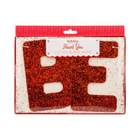 Packaged red glitter Be Mine banner pieces in clear sleeve